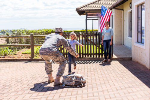 Mother and daughter greeting a military man with hugs at their home 