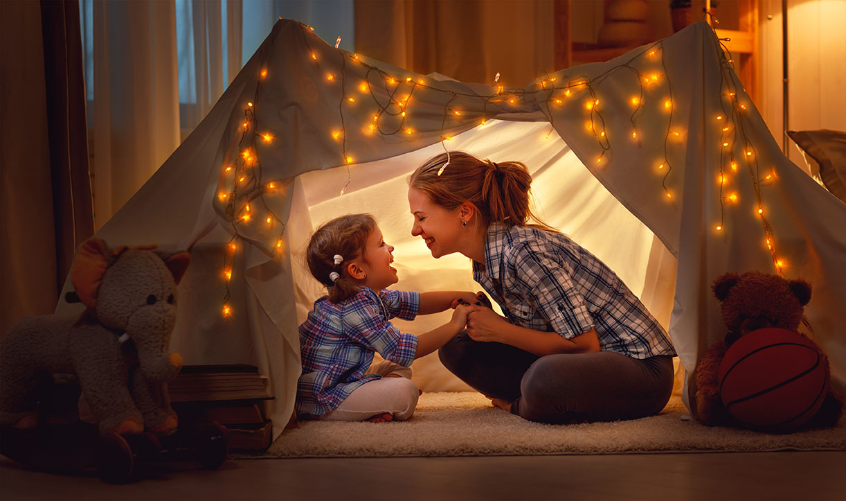 Mother and daughter in blanket tent with fairy lights
