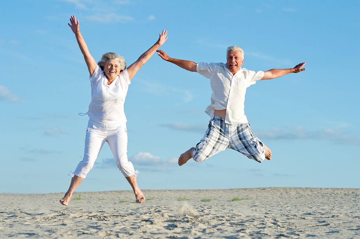 Elderly couple jumping joyfully on the beach