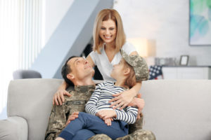 Military man sitting on white couch with son and wife